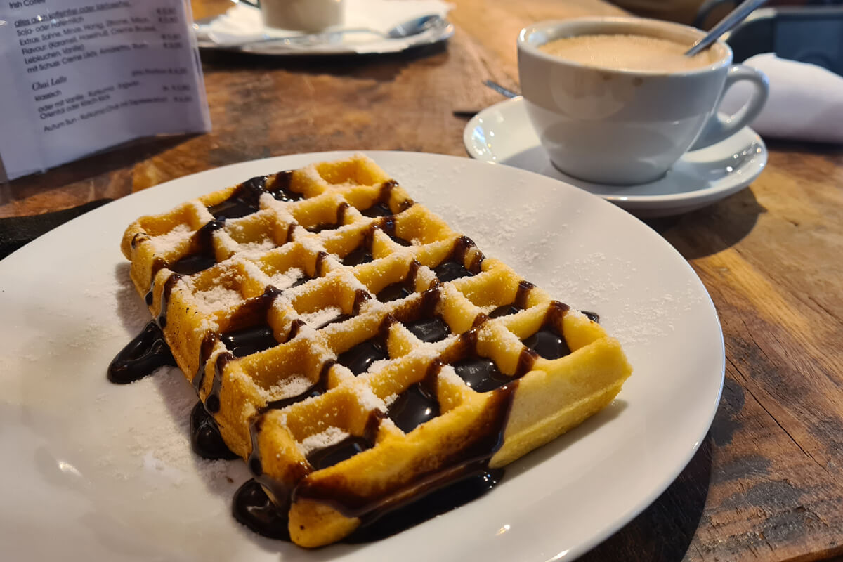 vegane Waffel mit Schokosoße und eine Tasse Cappuccino