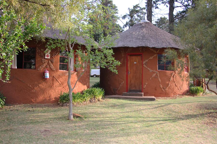 Traditionalle rote Rundhäuser mit Strohdach in der Malealea Lodge.