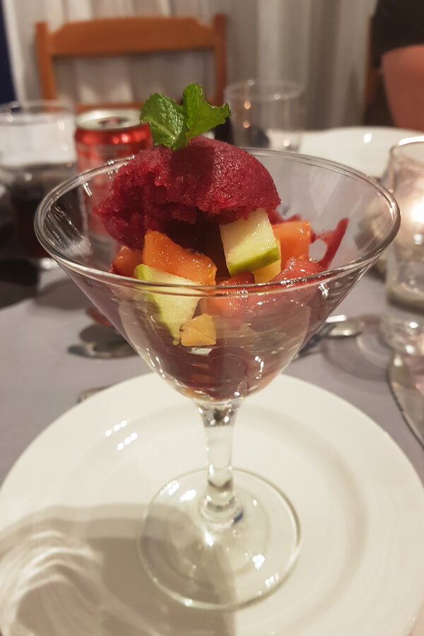 Obstsalat mit Sorbet serviert in einem Cocktailglas.