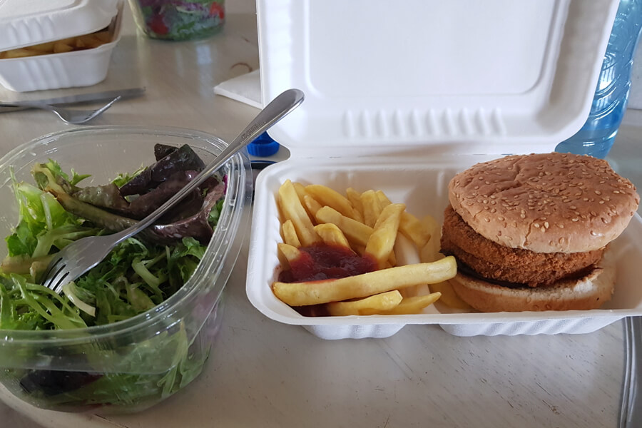 Veggie-Burger mit Pommes und Salat in Take-Away Schachtel.