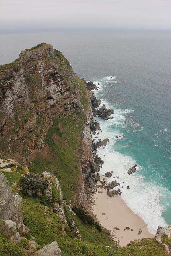 Steilklippe und Strand treffen auf das Meer am Cape Point.
