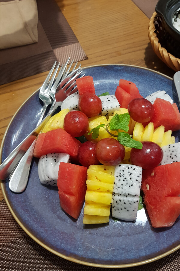 Eine gemischte Obstplatte mit Melon, Trauben, Ananas und Drachenfrucht.