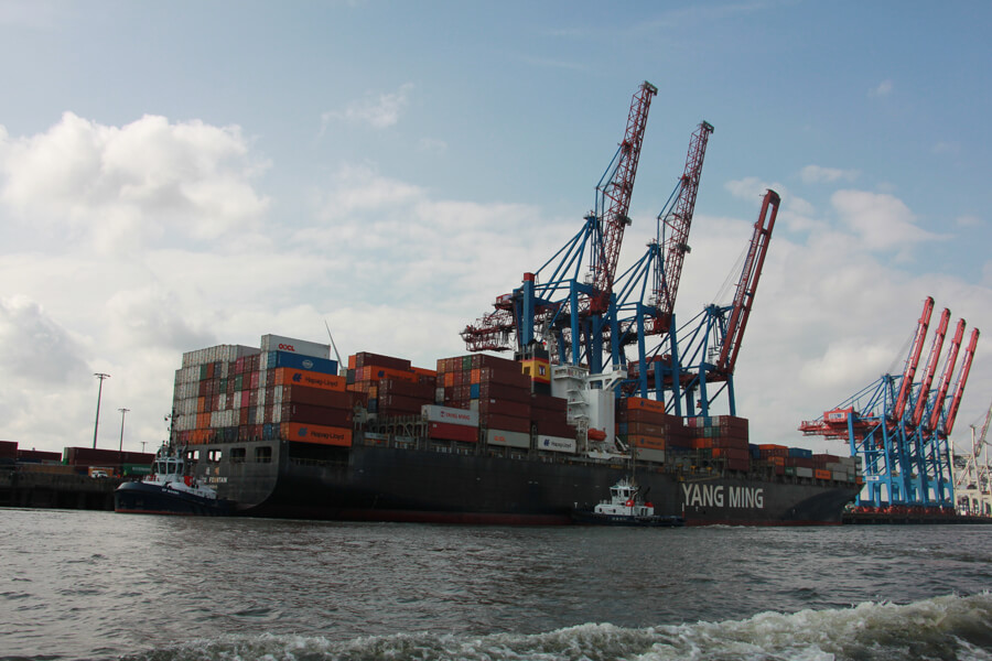 Ein großes Containerschiff im Hamburger Hafen legt bei den Entladekränen an.