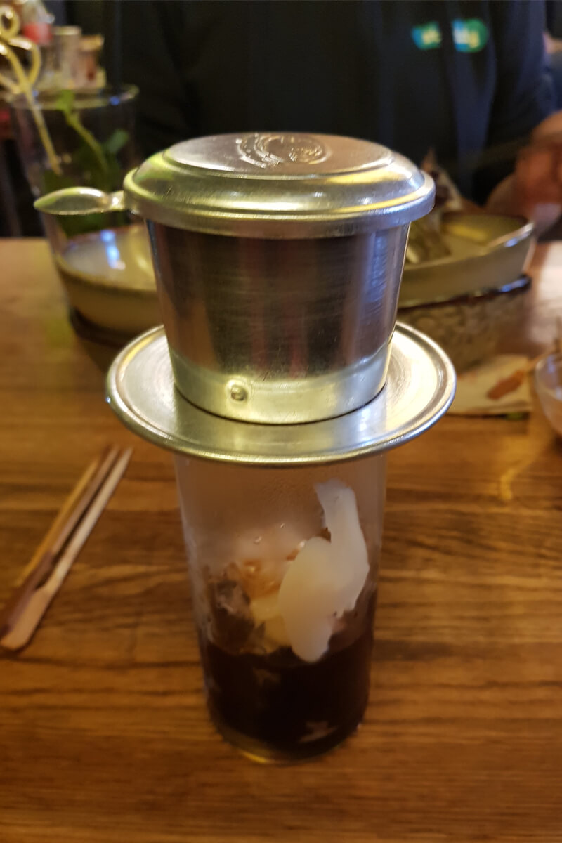 Typisch vietnamesischer Eiskaffee serviert mit einem Blechfilter über dem Glas.