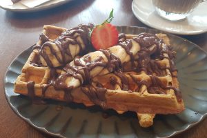 vegane Waffel mit Banane und Schokosoße in Noras Deli
