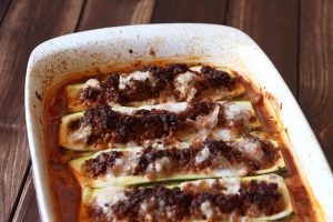 Aufflaufform mit veganem Hack gefüllten Zucchini auf Tomatensoße