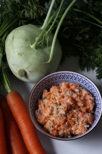Veganer Kohlrabi-Möhren Salat in einem kleinen Schälchen vor den rohen Zutaten