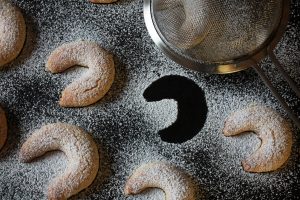 Vegane Vanillekipferl mit Puderzucker überstreut und einem Sieb