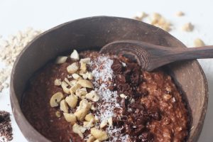 veganes Kokos-Schoko-Porridge in einer Kokosnussbowl mit Toppings