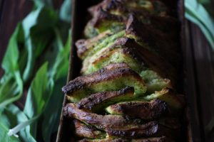 Veganes Kräuterfaltenbrot in einer Kastenform, deneben ein paar Bärlauchblätter
