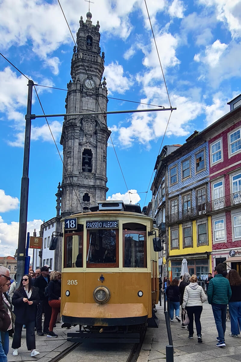 Eine gelbe Tram-Bahn vor dem Torre dos Clerigos.