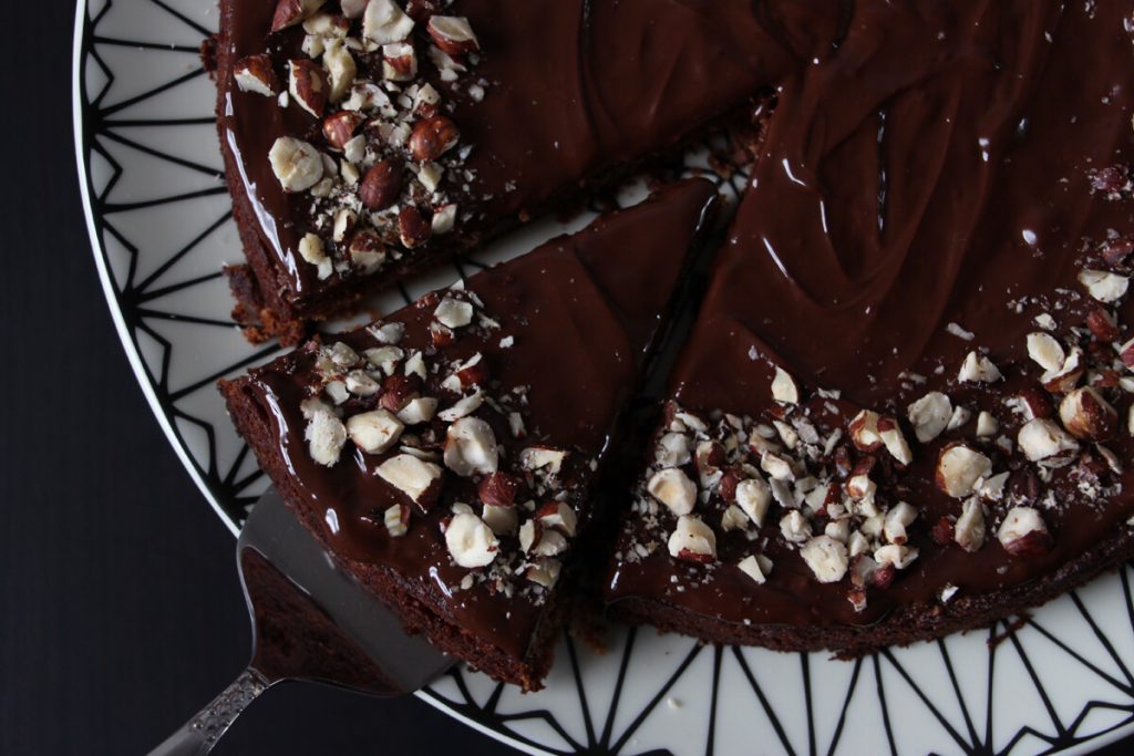 ein Stück veganer Nougatkuchen wird mit dem Tortenheber aus dem ganzen Kuchen genommen