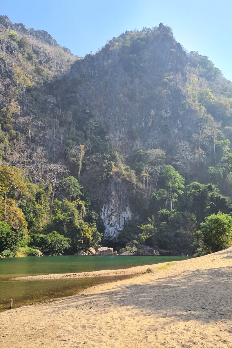 Sandstrand vor den Karstfelsen am Eingang zur Höhle.