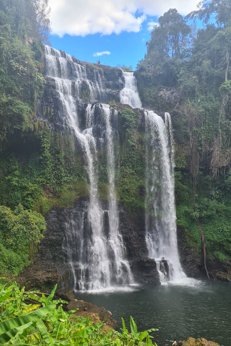 Der Tag Yeuang Wasserfall auf dem Bolaven Plateau fließt sanft über moosbewachsene Felsen