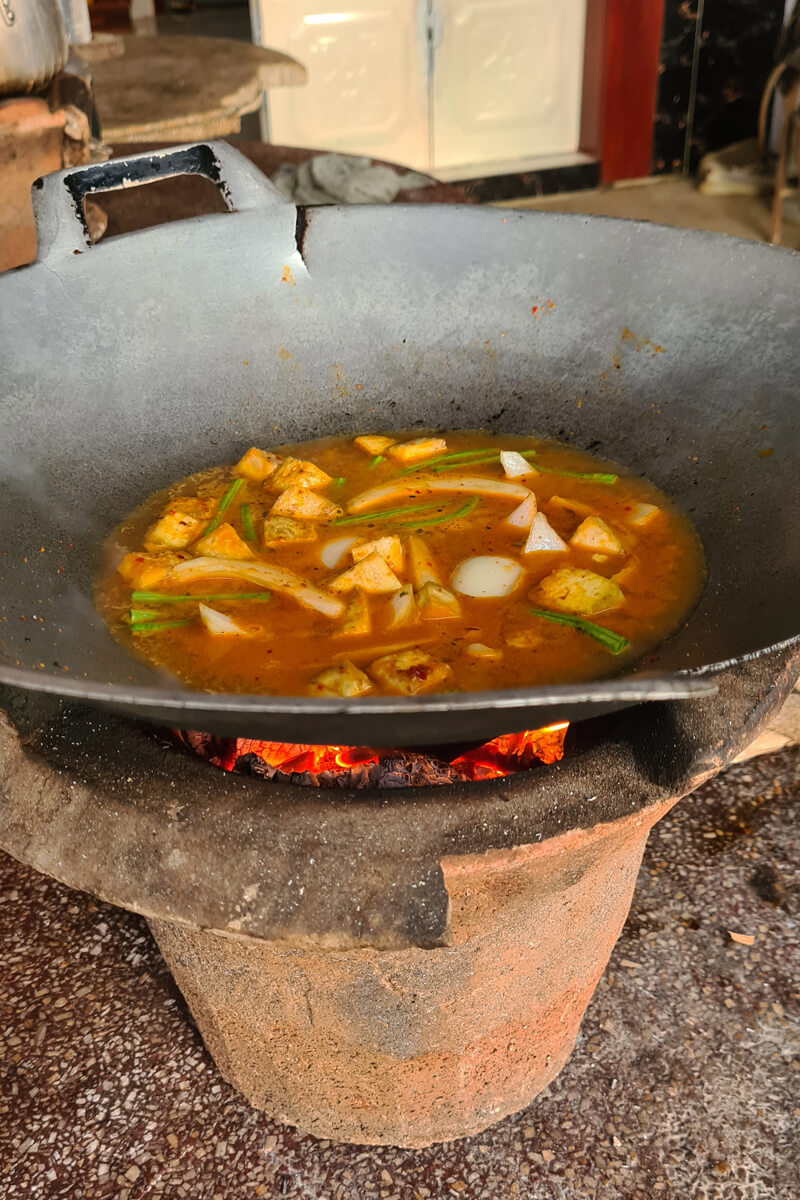 Das Curry wird im Wok direkt über der Holzkohle gegart.