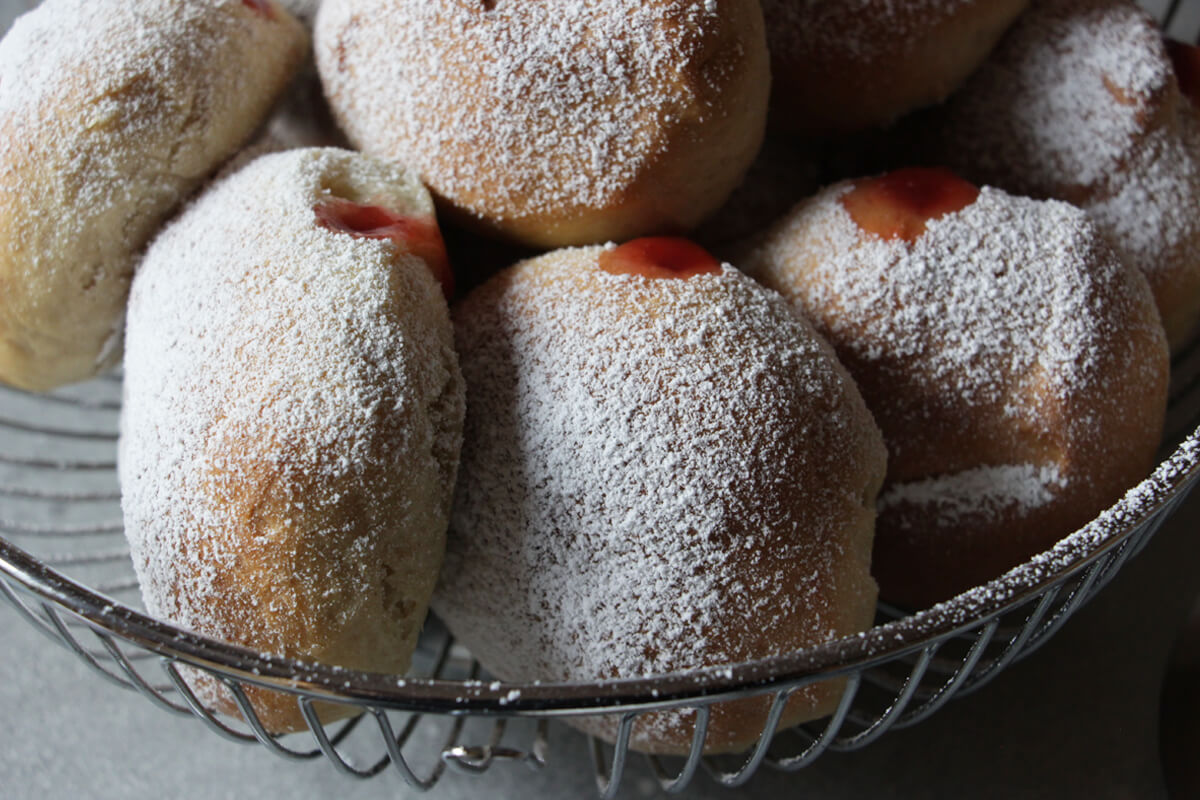 vegane Ofenberliner mit Erdbeerfüllung und Puderzucker in einem Brotkorb