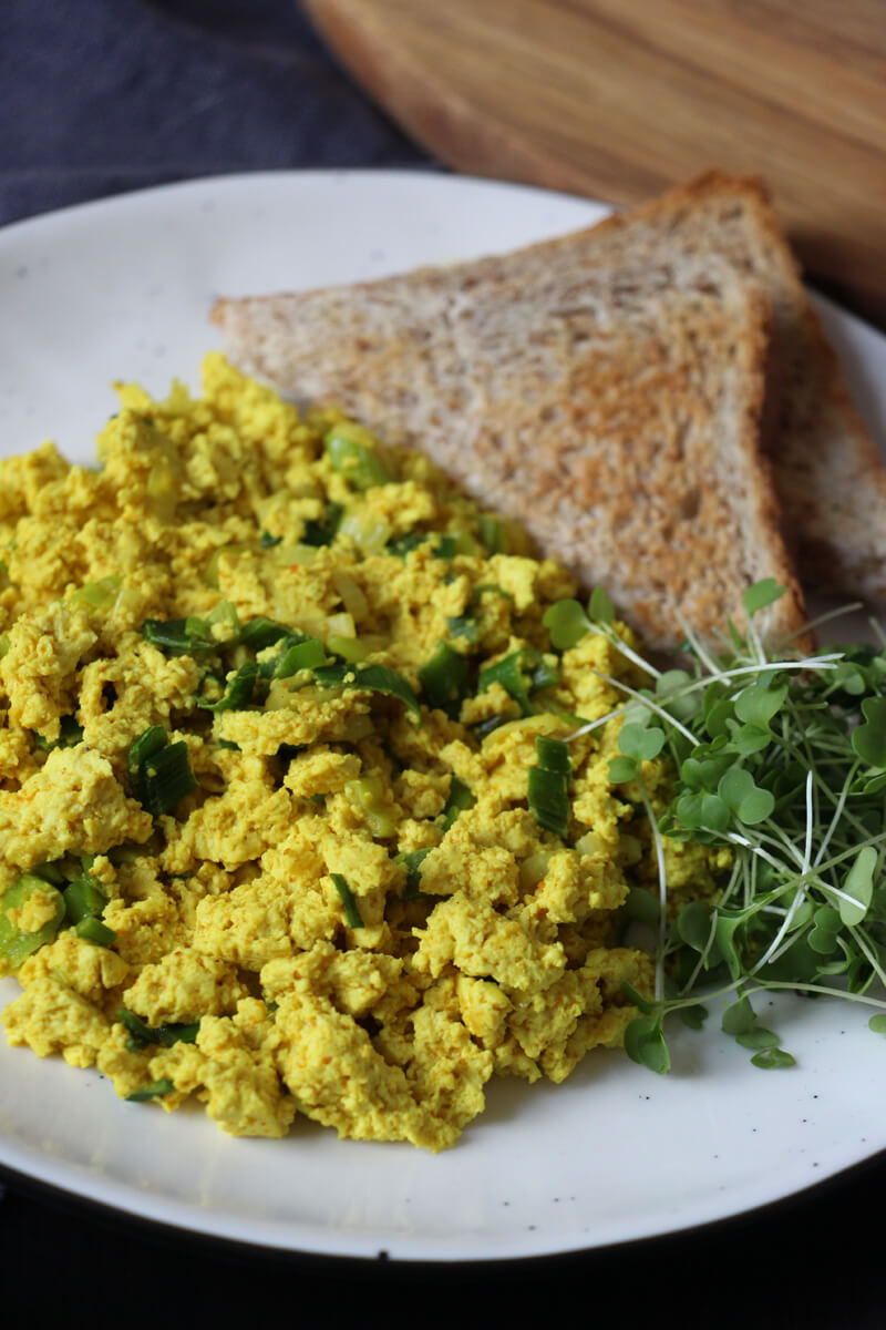 Ein Teller mit Scrambled Tofu, Toast und grünen Sprossen.