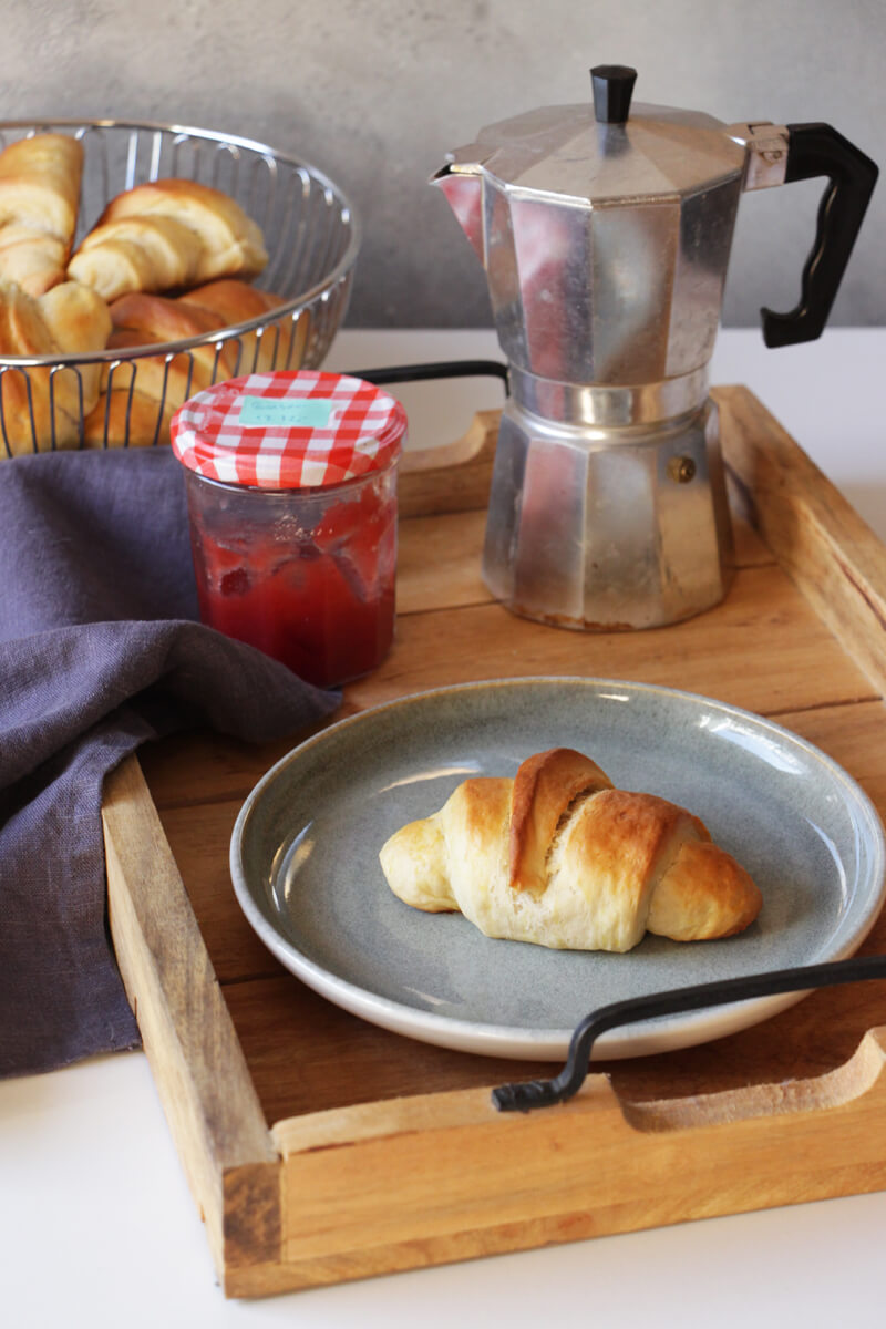 vegane Brioche Croissants auf einem Teller neben einer Espressokanne und einem Marmeladenglas