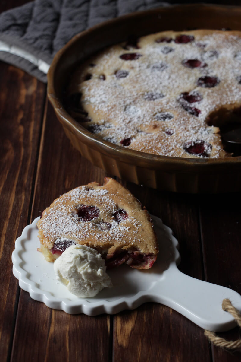 ein Stück veganer Clafoutis mit Kirschen und Vanilleeis