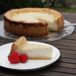 Rezept: veganer Käsekuchen Angeschnittener veganer Käsekuchen auf einer Platte mit einem Stück auf einem Teller davor