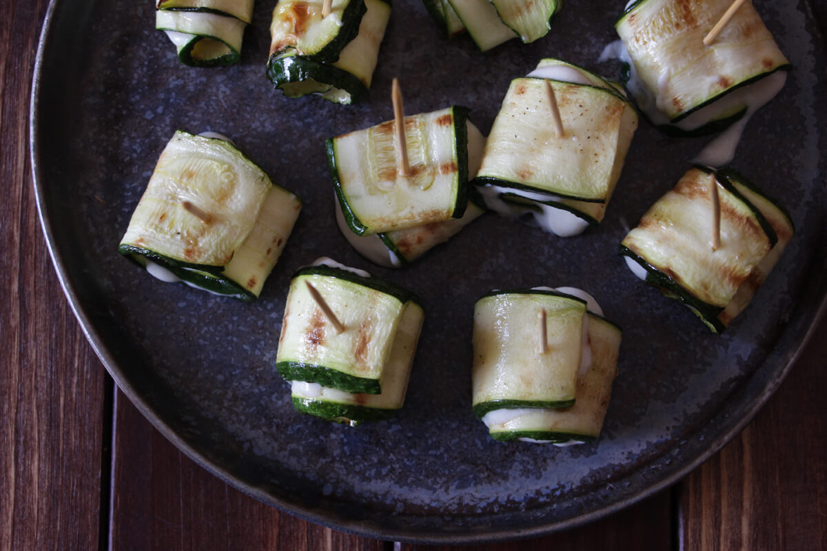 vegane Zucchiniröllchen mit Fetacreme auf einem Teller von oben fotografiert