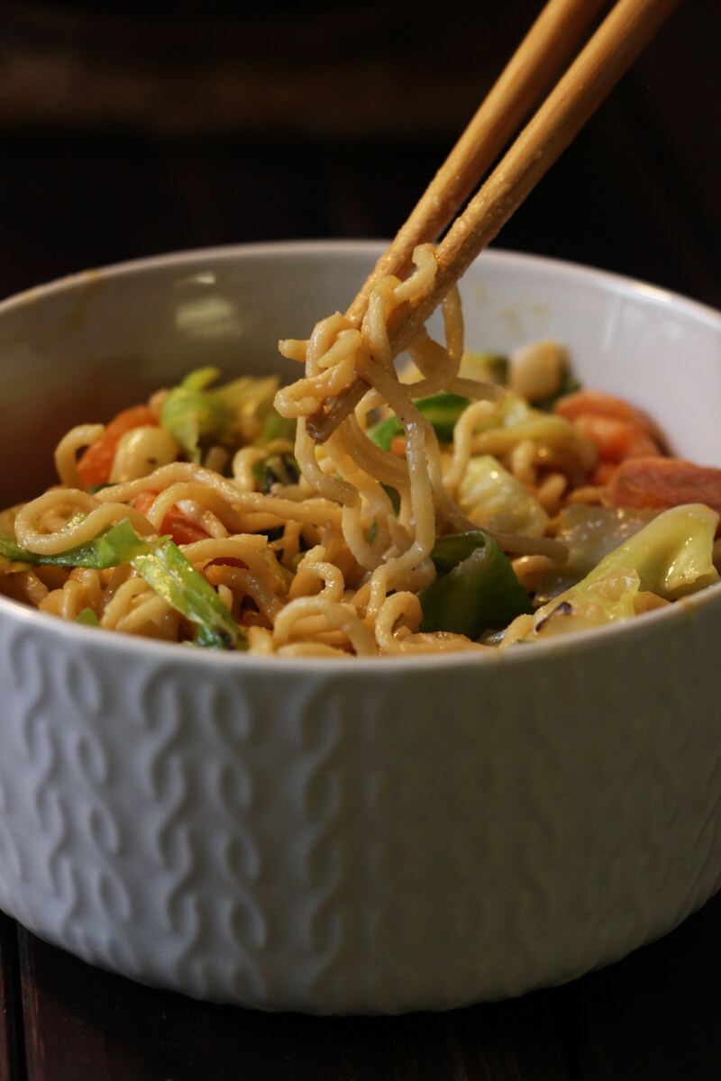 vegane Mie-Nudel-Wok-Pfanne mit Möhren und Spitzkohl in einem Schälchen mit Stäbchen